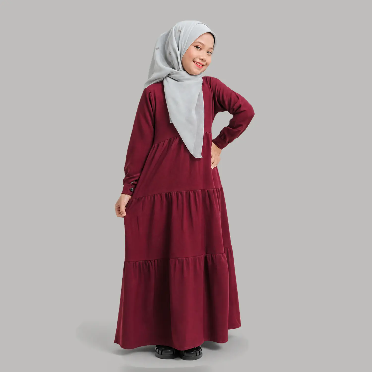 Side view of maroon tiered frill abaya for girls showing graduated frock tiers and long buttoncuff sleeves